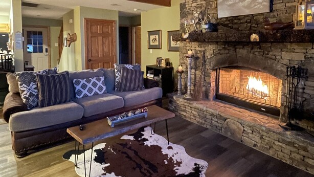 Un salón acogedor con chimenea de piedra, techo de madera y alfombra de cuero de vaca.