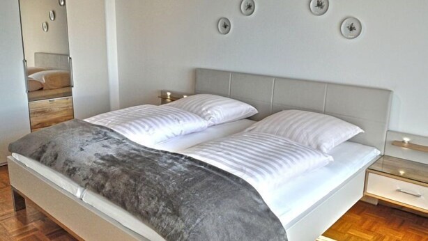 A modern bedroom with a bed, bedside tables, and a mirror. - Belvedere by Interhome (Manderscheid)