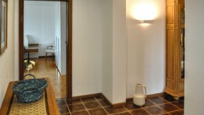 A hallway with a wooden floor, a white wall, and a door leading to another room. - Belvedere by Interhome (Manderscheid)