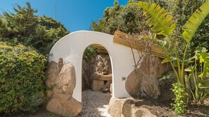 Un sendero que atraviesa un arco blanco rodeado de rocas y follaje.