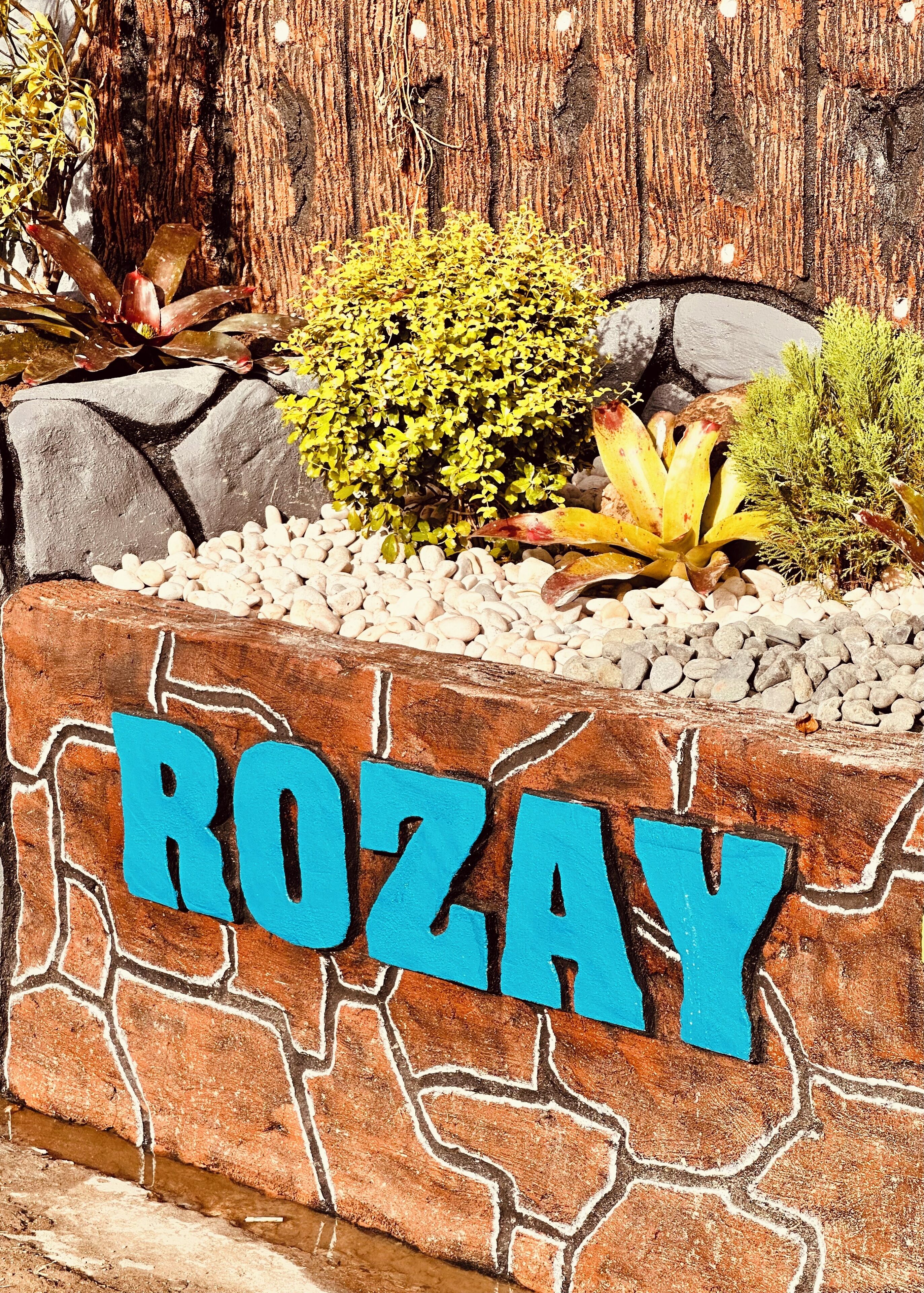 Un muro de piedra con la palabra "ROZAY" pintada en letras azules.