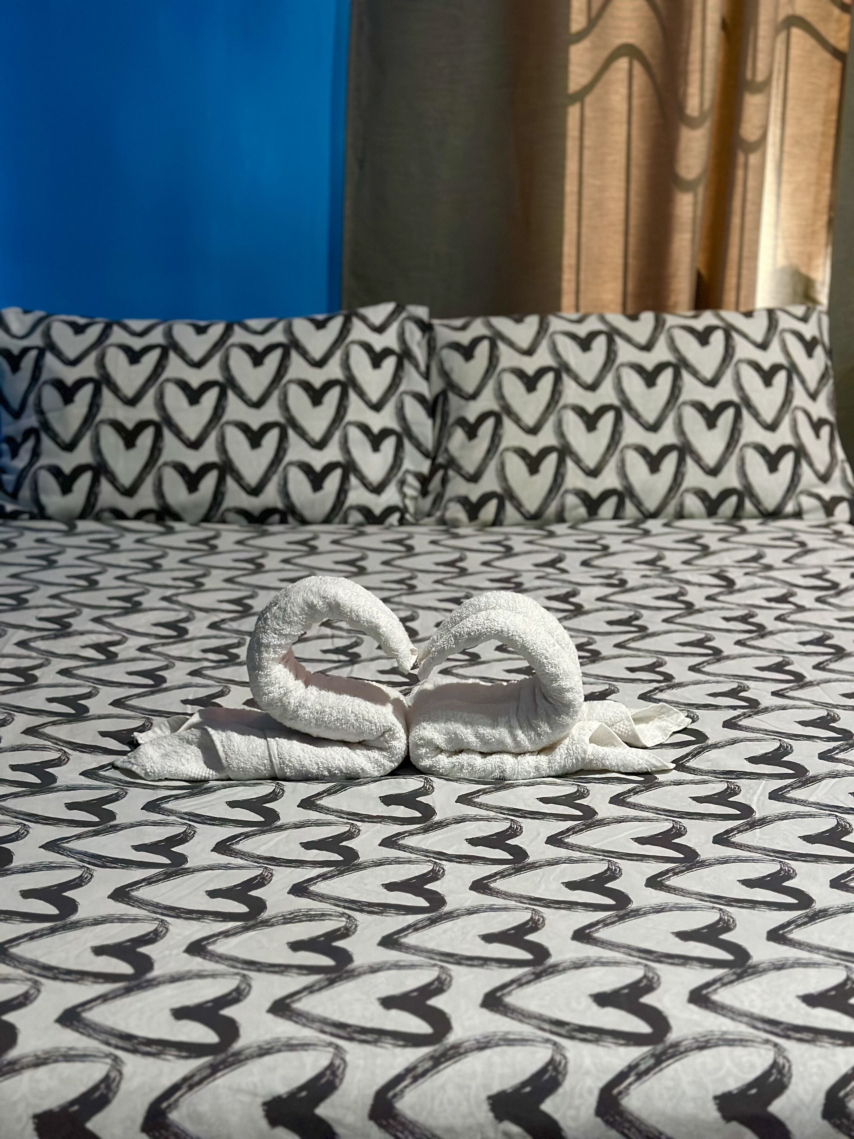 Ein Bett mit einem gemusterten Überwurf und herzförmigen Kissen.