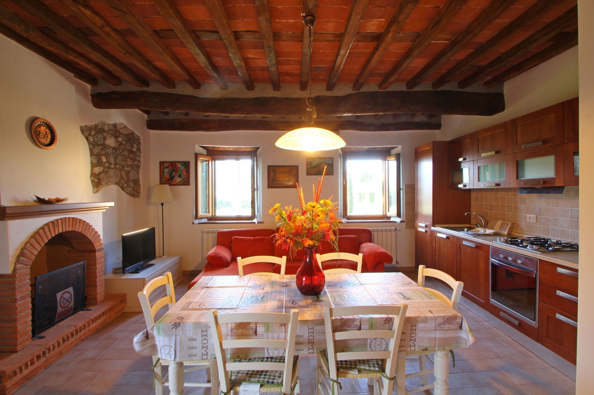 A dining area with a table set for four, surrounded by wooden chairs, a brick fireplace, and a stone wall.