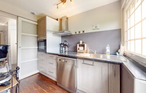 A modern kitchen with stainless steel appliances, a dishwasher, and a large window providing natural light. - Homerez - House in Vittefleur, garden. (Vittefleur)