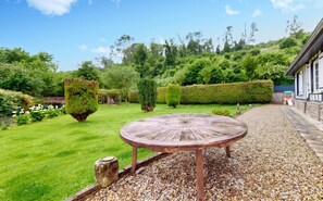 A garden with a wooden table and chairs, surrounded by a gravel path and greenery. - Homerez - House in Vittefleur, garden. (Vittefleur)