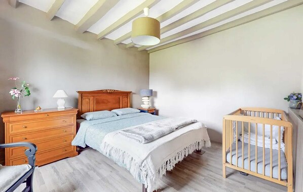 A bedroom with a wooden bed, a wooden dresser, a nightstand, a crib, and a ceiling with exposed beams. - Homerez - House in Vittefleur, garden. (Vittefleur)