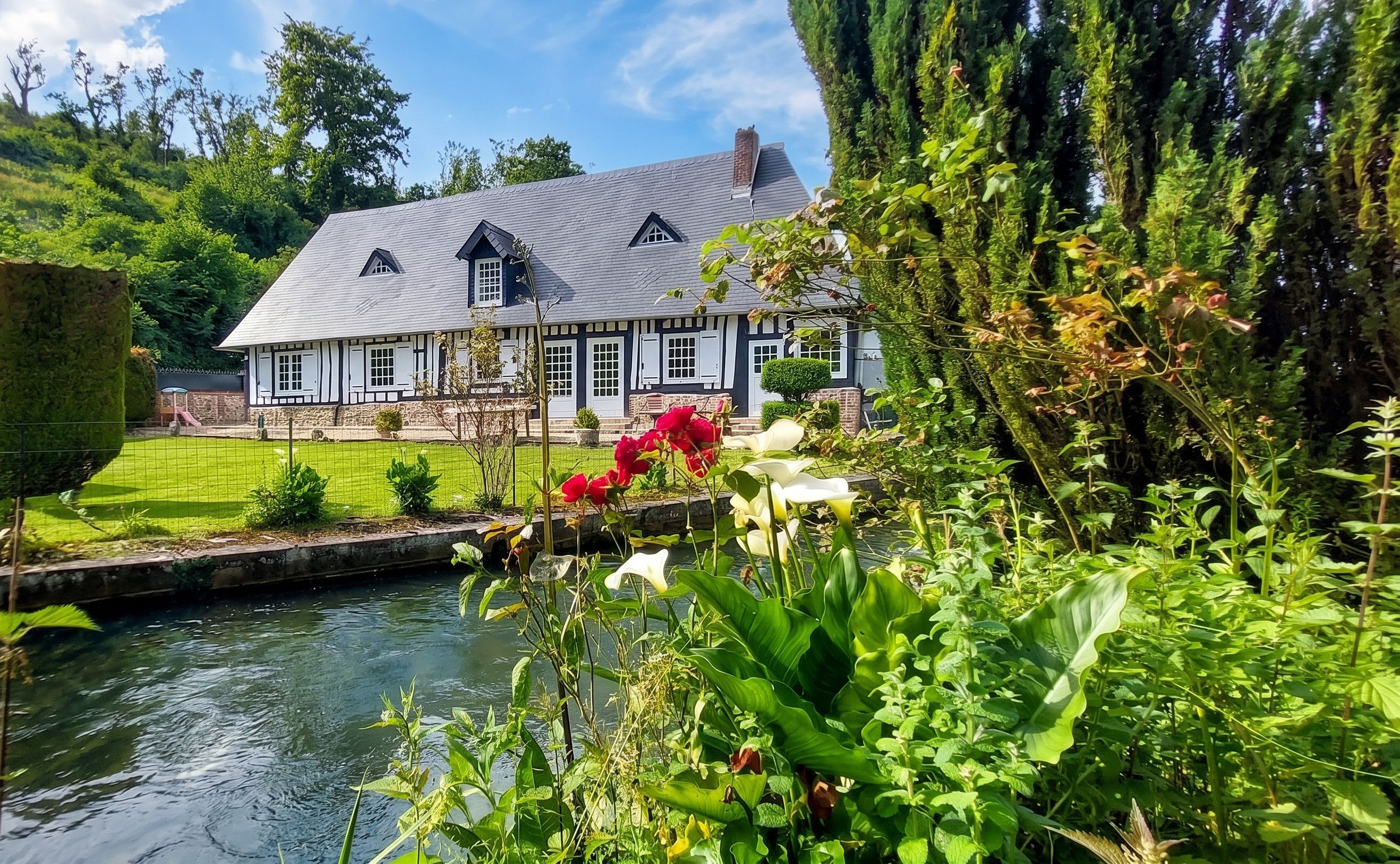 A traditional half-timbered house with a pond in the foreground.