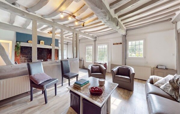 A spacious living area with a fireplace, multiple seating options, and a large window providing natural light. - Homerez - House in Vittefleur, garden. (Vittefleur)