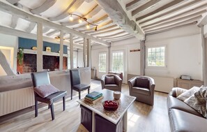 A spacious living area with a fireplace, multiple seating options, and a large window providing natural light. - Homerez - House in Vittefleur, garden. (Vittefleur)