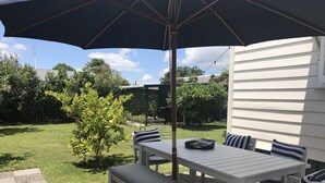 An outdoor patio with a table and chairs, a bench, and a large umbrella. - Bryce Cottage by Webb hotels (Leamington)