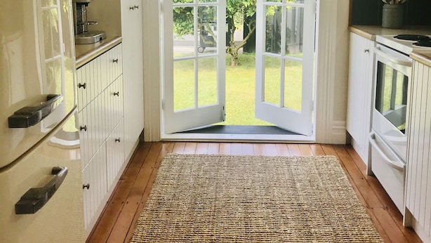 A kitchen with a large sliding glass door leading to a garden, wooden flooring, and white cabinetry. - Bryce Cottage by Webb hotels (Leamington)