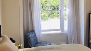 A bedroom with a large window, a chair, and a bed. - Bryce Cottage by Webb hotels (Leamington)