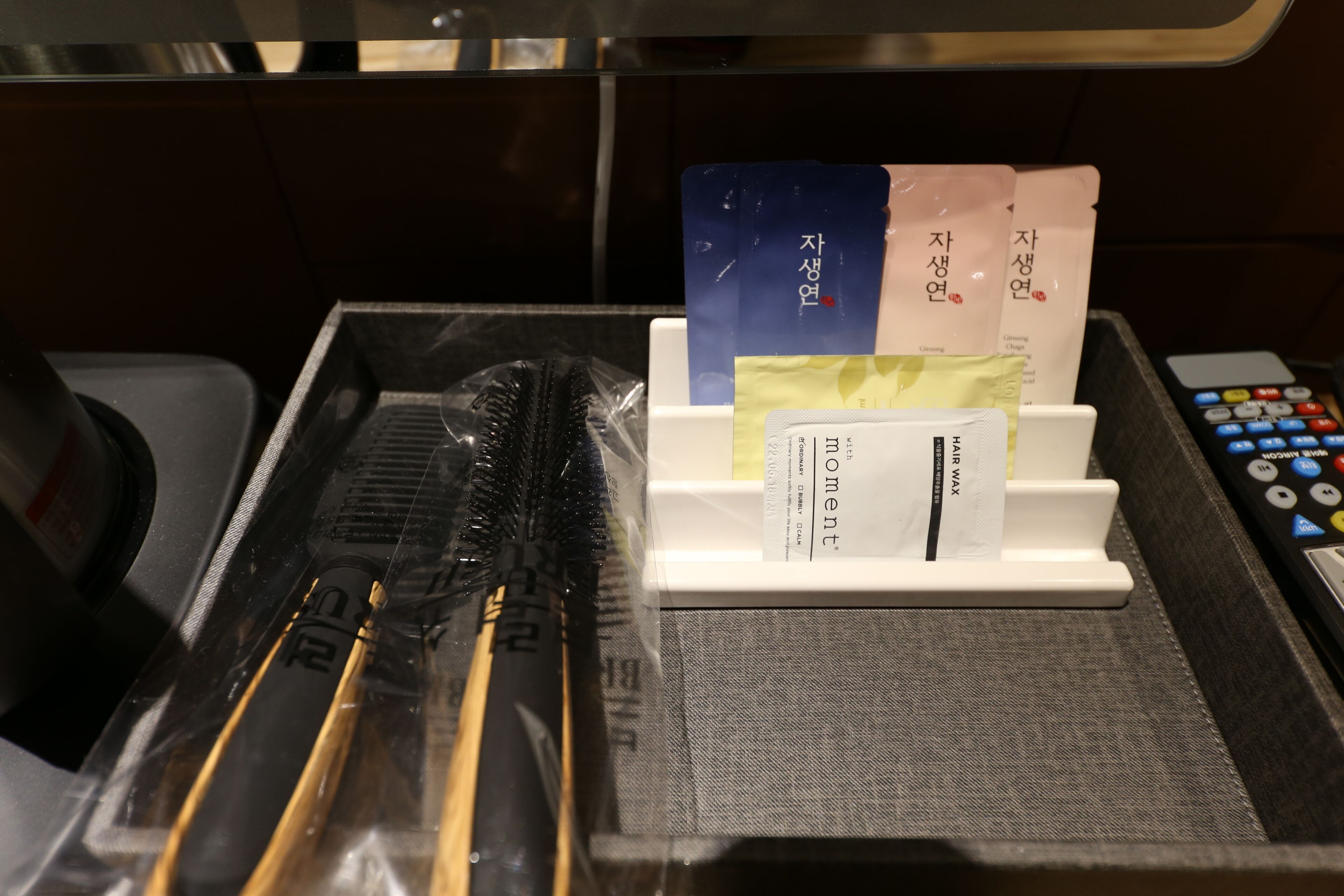 A tray with a remote control, a set of keys, and a cardholder with cards.