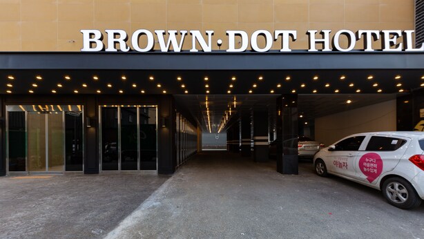 The entrance to the Brown-Dot Hotel with a clear view of the entrance doors and a car parked outside. - Brown Dot Hotel Cheonan (Cheonan)