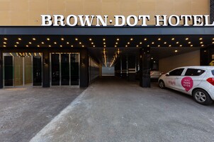 La entrada del Hotel Brown-Dot, con una vista clara de las puertas y un coche estacionado afuera.
