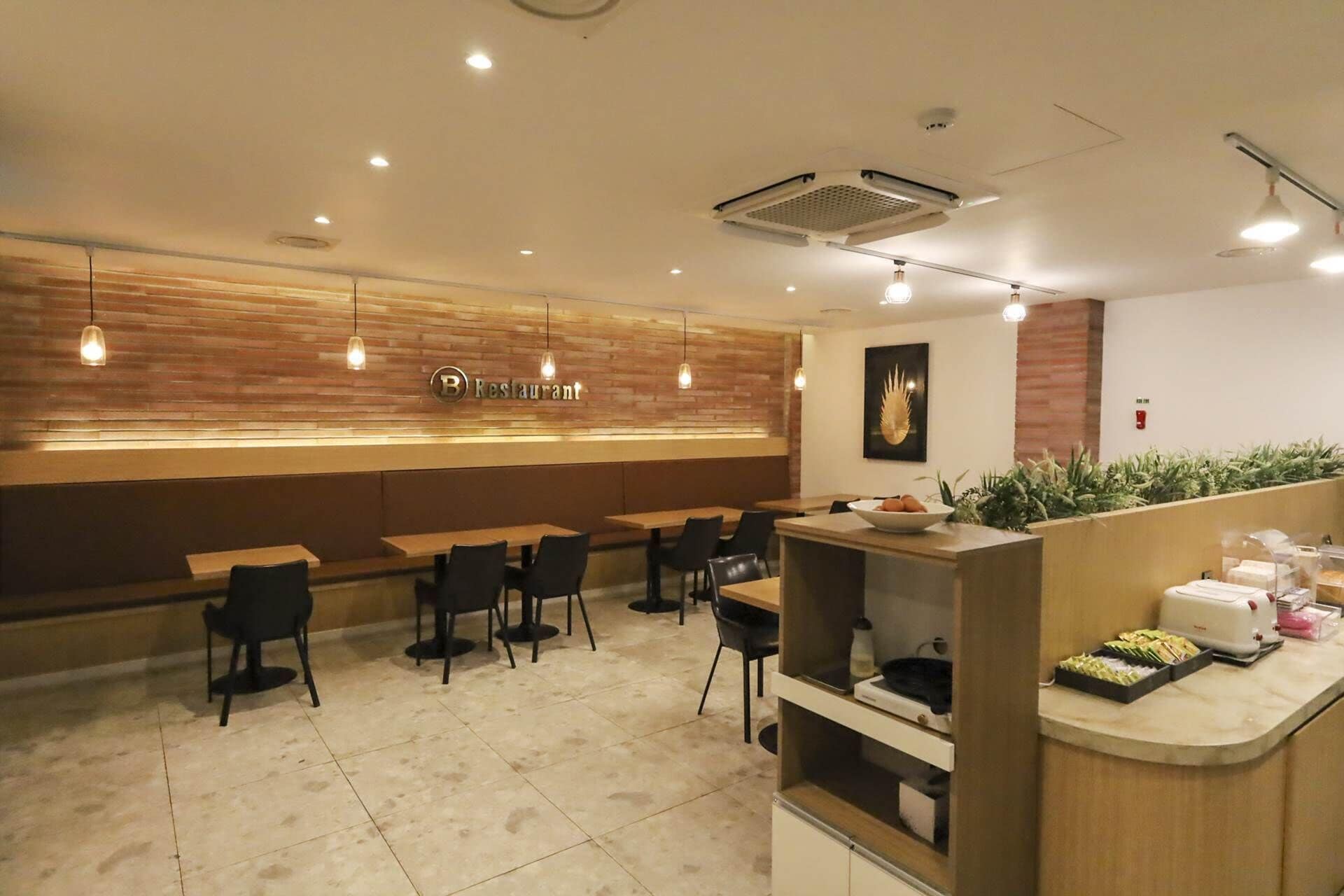 L'intérieur d'un restaurant avec un mur en bois, plusieurs tables et des chaises.