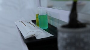 A bathroom counter with a tissue box, a green bottle, and a potted plant.