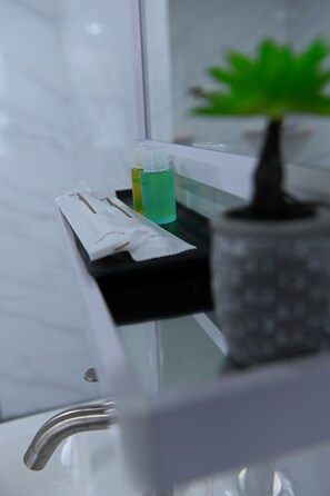 A bathroom counter with a tissue box, a green bottle, and a potted plant.