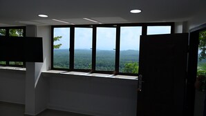 A room with large windows, a flat-screen TV, and a ceiling with recessed lighting.