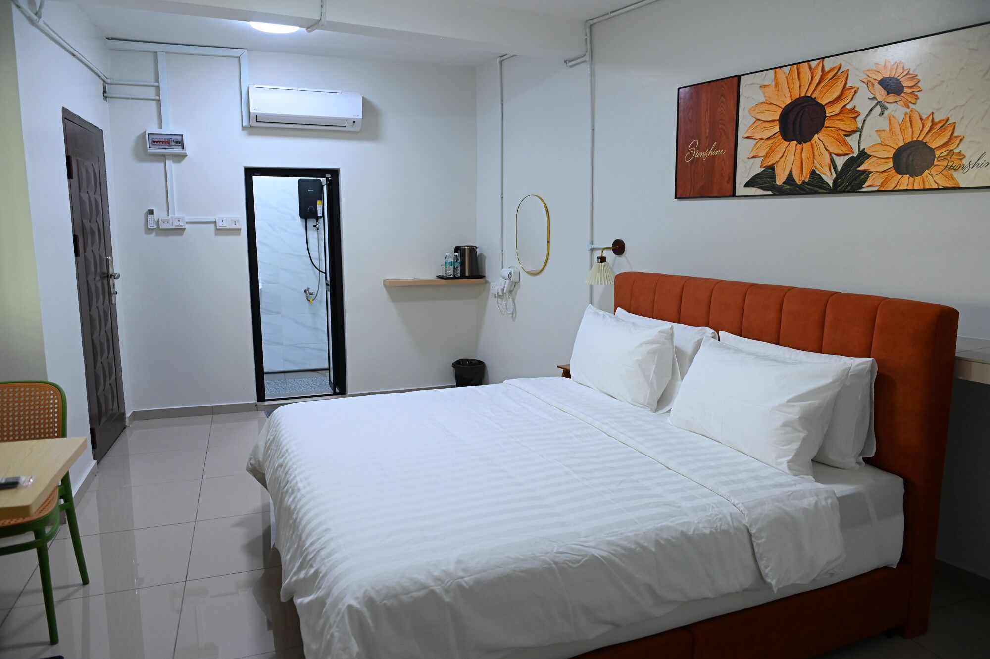 Habitación de hotel con cama, una silla, un escritorio, baño y un cuadro en la pared.