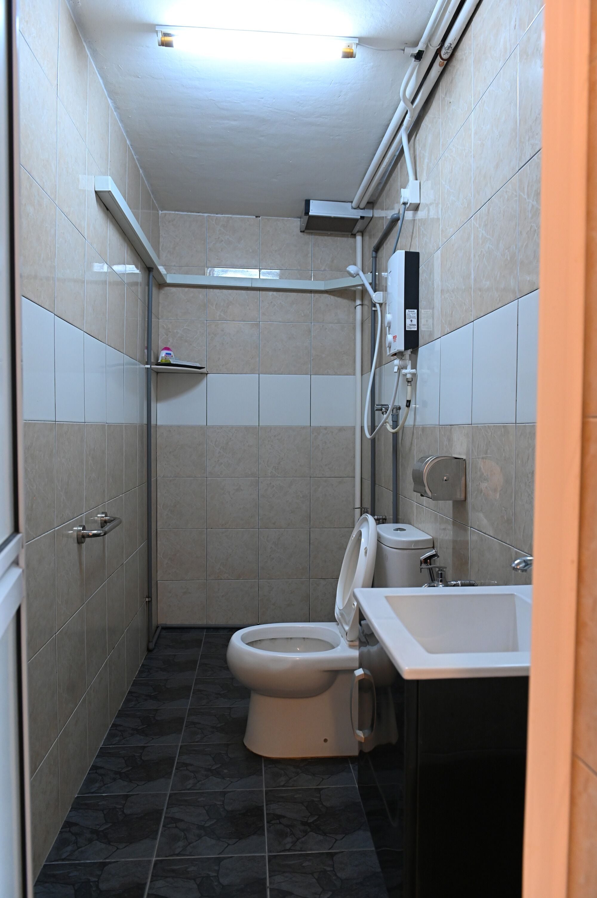 A small, tiled bathroom with a toilet, sink, and shower.