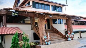 A two-story building with a wooden staircase leading to the entrance, a sign that reads "Welcome," and a red-tiled roof.