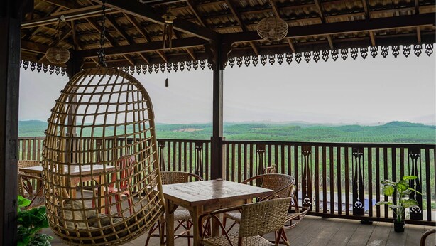 A covered outdoor seating area with wicker furniture, a wooden table, and a hanging chair.