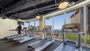 Un gimnasio con cintas de correr y una persona usándola.