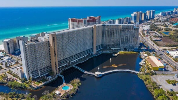 Un hotel grande con varios edificios altos, un puerto deportivo y vista al océano.