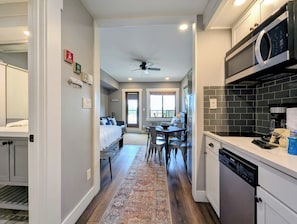 A compact hotel room with a kitchenette, a dining area, and a view of the outside.
