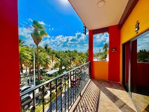 A balcony with a view of palm trees and a street. - Beach Front Fully Equipped Suite # 3 (Centro - Supmza. 001)
