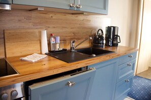 A kitchen with a wooden countertop, a sink, a kettle, a coffee maker, and a dish drying rack. - Am Wiesenblick - Müritz apartment (Röbel/Müritz)