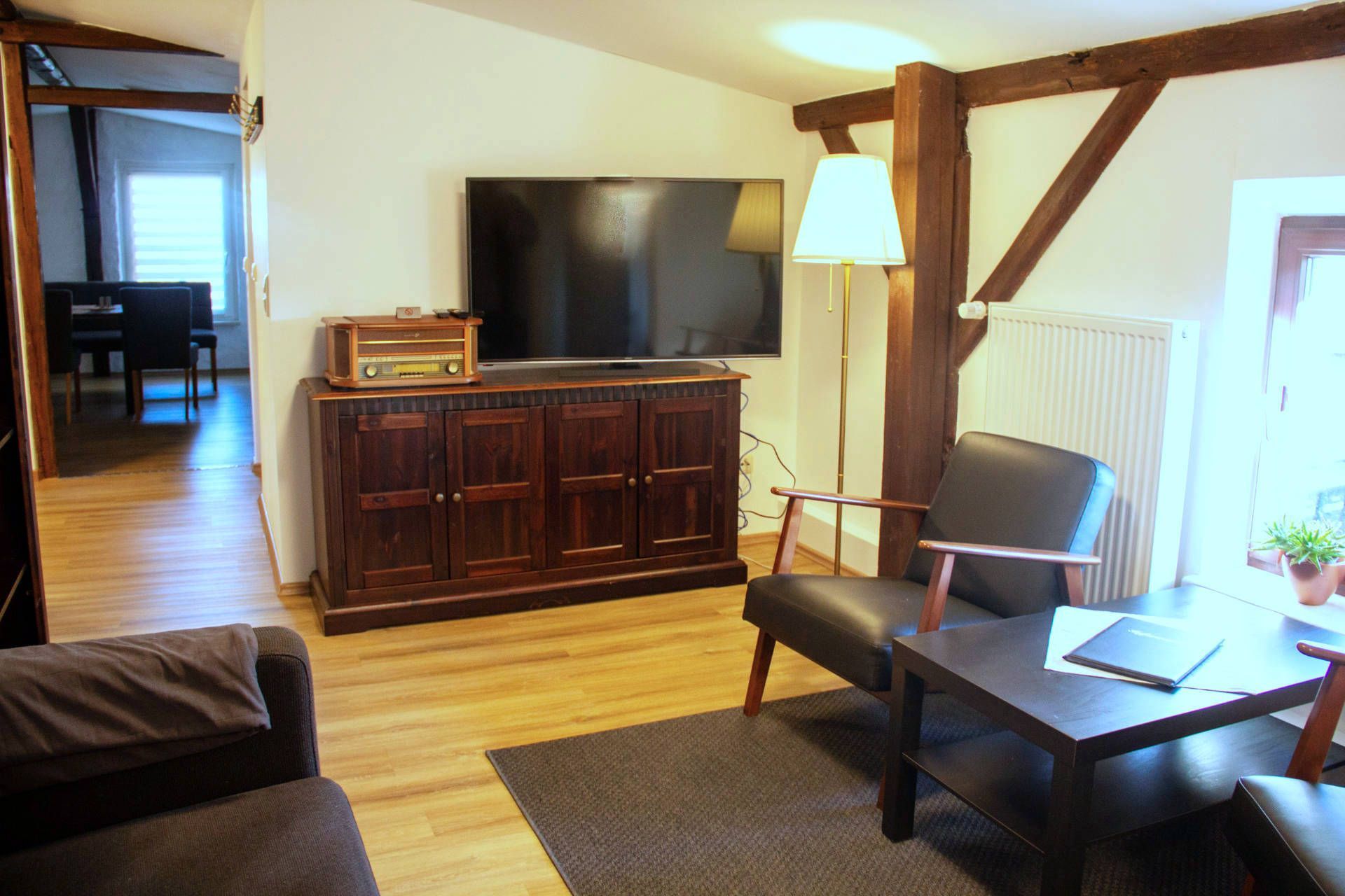 A living room with a wooden cabinet, a television, a chair, a table, and a lamp.