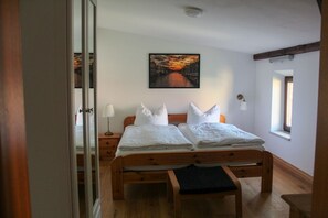 A double bed with white bedding, a bedside table with a lamp, a window with a view, and a painting on the wall. - Holiday ivy - Müritz apartment (Röbel/Müritz)