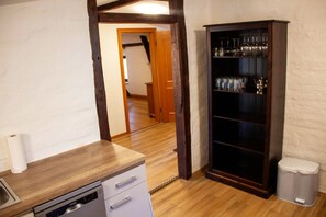 A kitchen with a wooden countertop, a dishwasher, and a cabinet with glassware.