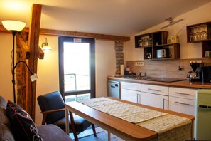 A compact kitchen with a dining area, a built-in oven, and a coffee maker.