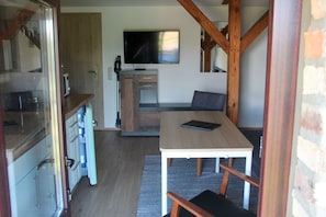 A compact kitchen with a microwave, a wooden table with a tablet, and a TV mounted on the wall. - Tenne 1 - Müritz apartment (Röbel/Müritz)