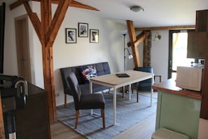A compact living space with a sofa, a small table, a chair, and a kitchenette area. - Tenne 1 - Müritz apartment (Röbel/Müritz)