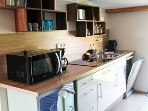 Une cuisine équipée d’un four à micro-ondes, d’un grille-pain, d’un évier et de placards.