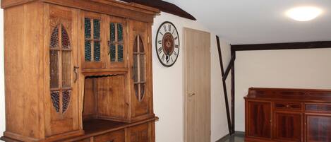 Een houten kast met glazen deuren, een wandklok en een houten bank.