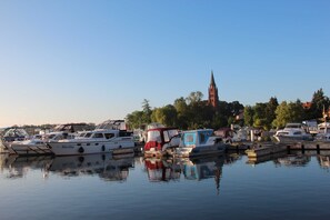 Een jachthaven met aangemeerde boten, een kerk op de achtergrond en rustig water dat de boten weerspiegelt.