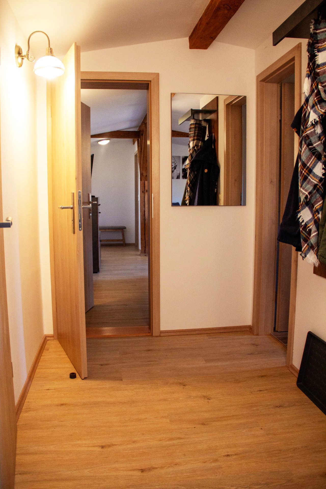 A hallway with wooden flooring, a bench, and a mirror on the wall.