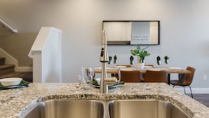 Eine moderne Küche mit einer Edelstahlspüle, einem Wasserhahn und einer Arbeitsplatte aus Granit.