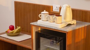 Eine Küchenzeile mit Kühlschrank, Kaffeemaschine und einer Schüssel Obst auf einer Holzausziehtafel.