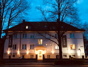 A large, two-story building with a symmetrical facade, multiple windows, and a central entrance. - Hotel Cocco Bello Smart Check in (Ludwigsburg)