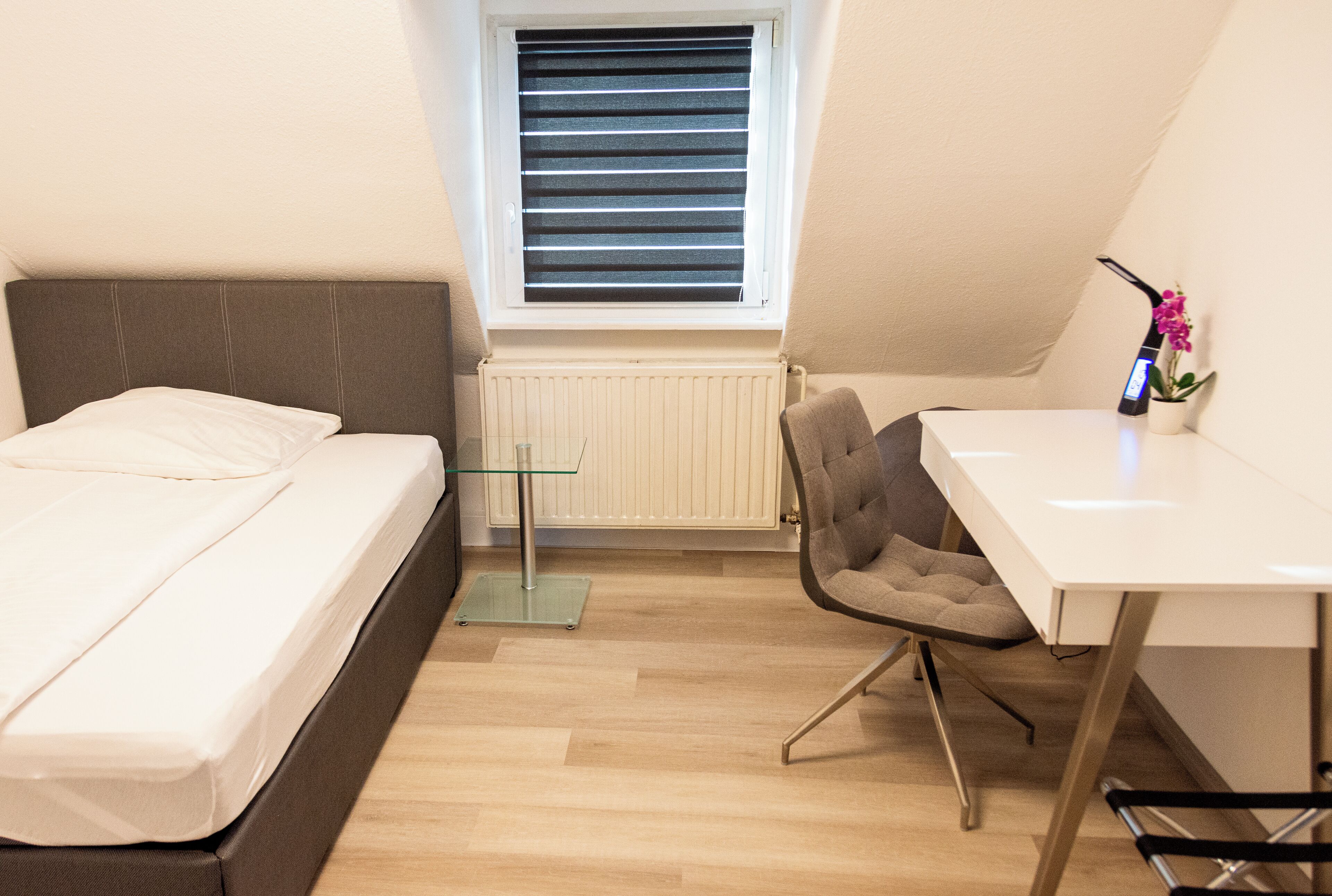 A bedroom with a bed, a desk, and a chair.