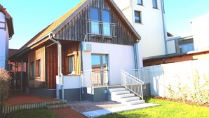 Un bâtiment à deux étages doté d’une façade en bois, d’un balcon et d’un escalier menant à l’entrée.
