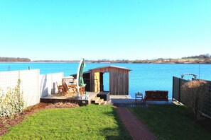 Una terrazza sul lago con posti a sedere all'aperto, una piccola struttura in legno e una vista limpida del lago.