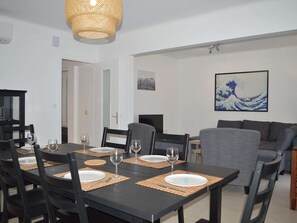 A dining area with a black table set for four, surrounded by chairs. There is a woven light fixture above the table.