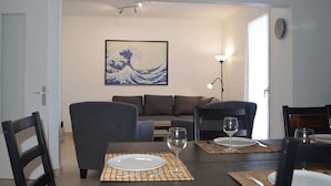 Un comedor con una mesa dispuesta para dos, un sofá y un cuadro de una ola en la pared.